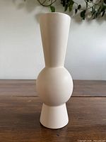 Front view of off-white ceramic vase with central sphere and tapered top and base
