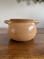 Front view of tan painted pottery crock with both handles visible