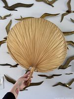 Front view of woven palm fan held by hand