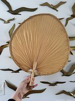 Front view of large woven palm fan held against wall