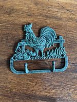 Full view of cast metal rooster wall hook with dual hooks