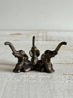 Front view of cast metal three-elephant stand