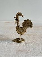 Left profile of metal rooster on pedestal