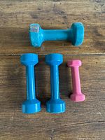 Four vinyl-coated dumbbells on wooden surface