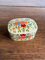 Top view of cream paper-covered trinket box with painted floral design