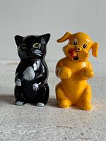 Front view of black cat and yellow dog plastic shakers standing side by side