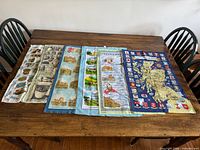 All six Scottish printed tea towels laid out overlapping on table