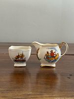 Creamer and sugar front view showing sailing ship and canoe scenes
