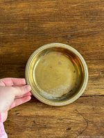 Top view of round brass dish with beaded rim