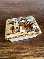 Lid showing full village street scene artwork
