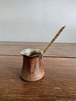 Side view of hammered copper Turkish coffee pot showing handle attachment and body texture