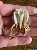 Full view of rose brooch front showing cream petals and gold-tone leaves and stem