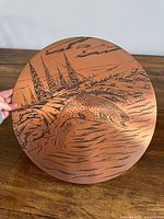 Front of round copper plaque with etched trout design