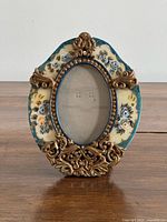 Front view of ornate oval resin frame showing floral design and opening