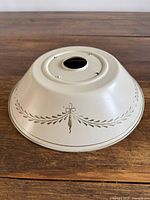 Top view of cream metal lampshade showing center fitter opening and stencil