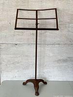 Full view of rusted metal music stand with paw base