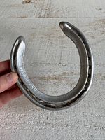 Front view of silver tone horseshoe showing brand stamp "KINGS PLATE"