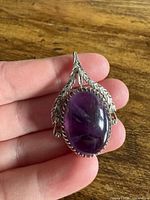 Front view of sterling silver pendant showing purple cabochon and leaf border