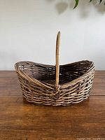 Side view of oval woven wicker basket with tall handle showing weave and patina