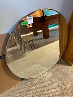 Full view of round mirror leaning against wall, reflective surface visible