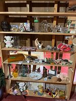 Overall view of shelving with assorted glassware, ceramics, jewelry box, textiles, and decor