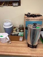Group view showing coffee urn, kettle, beverage dispenser, box of canning jars and Bernardin lids
