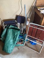 Lot overview showing chairs, green tarp, bungee cords, slat chair