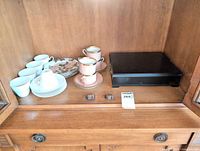 Group view of Fitz and Floyd cups and saucers, Rosenthal cups and saucers, Peony plates, and Bentley tea case