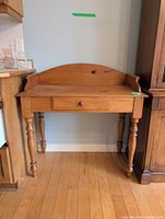 Front view of wood console table showing drawer, backsplash and turned legs