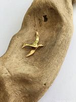 Front view of gold bird pendant on driftwood