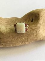 Front view of ring on wood display, showing opal and side stones