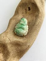 Front view of carved jade Buddha pendant on wood background