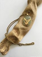 front view of pendant on chain displaying gold plated bird overlay