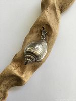 Full view of pendant on driftwood showing overall design and bail