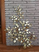 Full view of metal leaf wall sculpture against brick wall