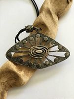 Front view of eye-shaped hammered pewter pendant on cord