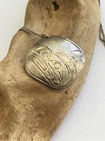 Close-up of etched sterling pendant on driftwood