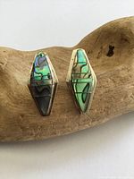 Front view of both sterling silver abalone inlay earrings on driftwood