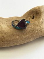 Front view of sterling silver ring showing purple glass center and abalone inlay