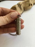 Pendant held in hand showing size, detailed relief design and cap