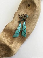 Front view of both turquoise inlay earrings on wood prop