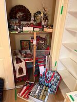 Closet overview showing wreath, wooden shelf, stockings, fabric, wrapping paper, gift bag, tabletop tree and other items