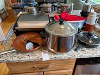 Overview showing grill, stockpot, copper pan, thermometer, mitts, dispensers