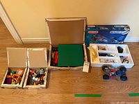 Overall lot view showing Meccano box, parts tray, assembled vehicle, two Lego boxes, green baseplate
