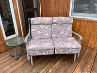 Loveseat with cushions beside side table on deck