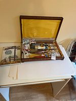 Overall view of open wooden box on table with book and paper