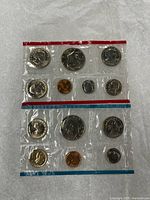 Front view of both sealed pliofilm packs showing obverse of Philadelphia (blue) and Denver (red) coins