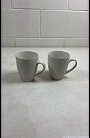 Front view of both textured off-white mugs