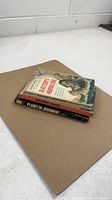 Stack of three paperback novels showing thickness and edges