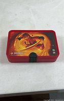 Closed red LEGO Ninjago Kai box showing lid graphic and latch